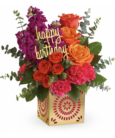 Flower bouquet of orange roses, fuchsia stock and pink carnations in a metallic cube vase.
