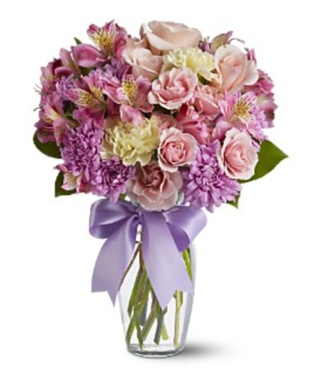 Lavender and pink flowers in a clear glass vase tied with a lavender bow.