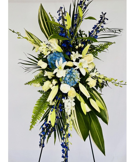 Blue and white flowers arranged on an easel with greenery.