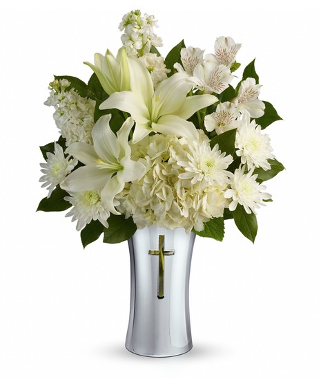 White hydrangea and lilies in a ceramic vase with a cross cut-out.
