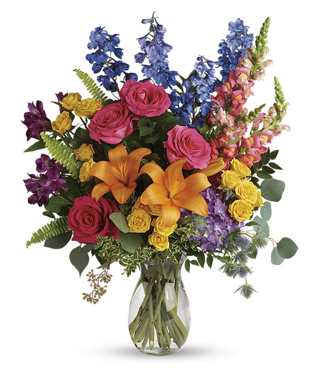 Clear glass vase of purple hydrangea, pink roses, orange lilies and more. 
